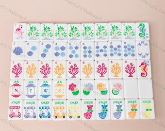 May include: A set of white Mahjong tiles with colorful illustrations. The tiles feature images of palm trees, seashells, coral, and seahorses. Some tiles have the word "JOKER" and images of golf carts and llamas.