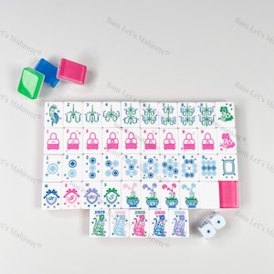 Puede incluir: Un juego de Mahjong completo con fichas blancas con dise&ntilde;os rosas, azules y verdes. Incluye dados y soportes para fichas de colores. Las fichas muestran varios s&iacute;mbolos y n&uacute;meros.