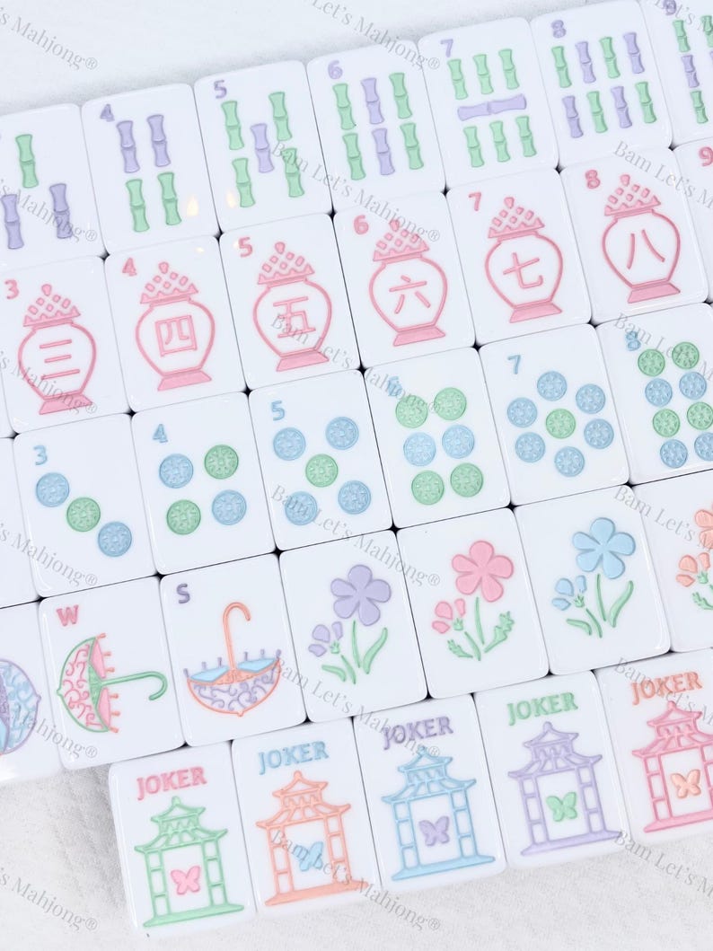 May include: A collection of white Mahjong tiles with various symbols and numbers in green, purple, pink, and blue. The tiles feature bamboo, flower, and umbrella designs, along with the word "JOKER".