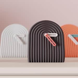 Peut inclure: Une horloge moderne et minimaliste avec un cadran en forme d'arche gris foncé et une trotteuse saumon. L'horloge a une aiguille des minutes et des heures blanches. Deux autres horloges sont visibles en arrière-plan, une blanche et une orange.