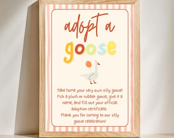 May include: A framed sign with the words "adopt a goose" in colorful letters. The sign features a cartoon goose holding a balloon and text that reads "take home your very own silly goose!" and "thank you for coming to our silly goose celebration!"