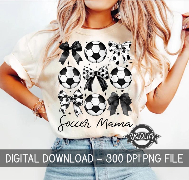 Puede incluir: Una camiseta blanca con un dise&ntilde;o en blanco y negro de balones de f&uacute;tbol y lazos. El texto "Soccer Mama" est&aacute; impreso en la camiseta.