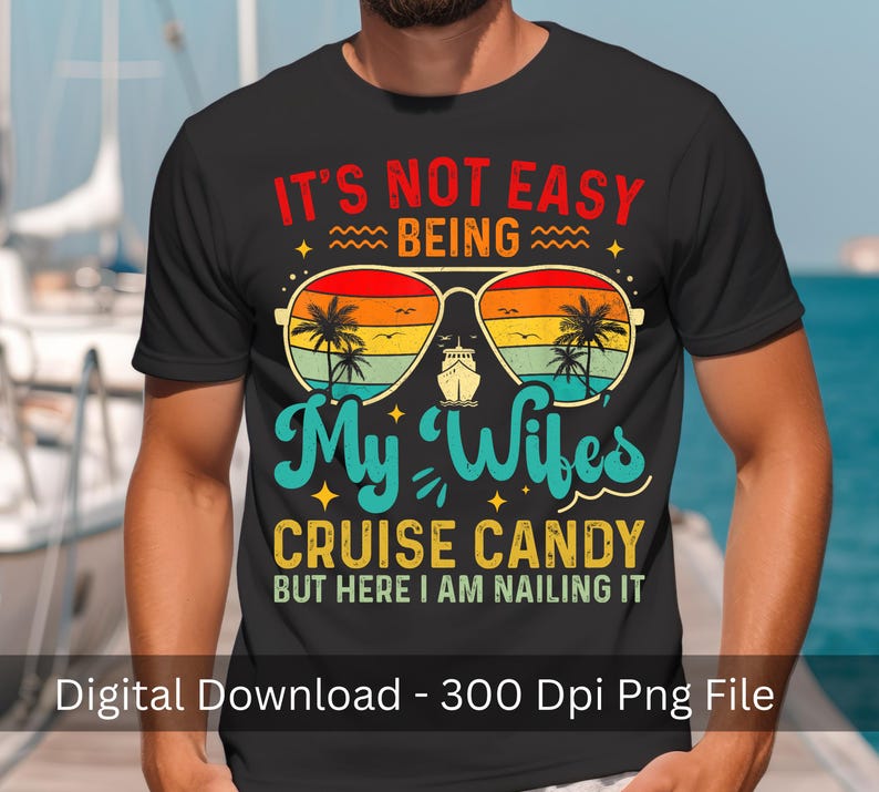 May include: Black t-shirt with a colorful graphic design. The design features sunglasses with a sunset scene, palm trees, and a cruise ship. Text includes "IT'S NOT EASY BEING My Wifes CRUISE CANDY BUT HERE I AM NAILING IT."