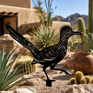May include: A black metal silhouette of a roadrunner bird featuring intricate cut-out details on the feathers and body. The bird is depicted in a running pose with a long tail and a crest on its head, mounted on a stake for outdoor display.