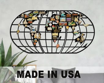 May include: Black metal world map wall art with colorful travel-themed pins. The map features a grid design and is decorated with miniature landmarks, hot air balloons, and other travel icons. The text "MADE IN USA" is visible.