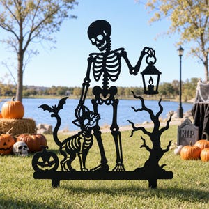 May include: A black metal yard stake silhouette featuring a skeleton holding a lantern, standing next to a skeletal cat with bat wings. The design includes a small jack-o'-lantern and a bare tree, all connected by a flat base with two stakes.