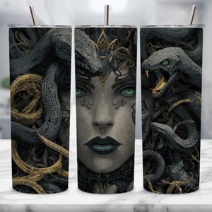 May include: A stainless steel tumbler featuring a detailed illustration of Medusa. The artwork depicts Medusa's face with snakes, in shades of gray, black, and gold. The tumbler includes a silver straw and is designed to hold cold beverages.