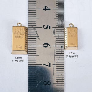 May include: Two gold bars, one measuring 1.5 inches and weighing 1.0 grams, and the other measuring 1.2 inches and weighing 0.7 grams. Both bars are labeled "FINE GOLD 999.9 1Kg".