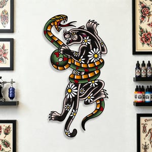 Pode incluir: Uma pantera negra com detalhes de margaridas brancas está entrelaçada com uma cobra verde e amarela. A pantera e a cobra estão em uma pose de luta. A obra de arte é ao estilo das tatuagens tradicionais.