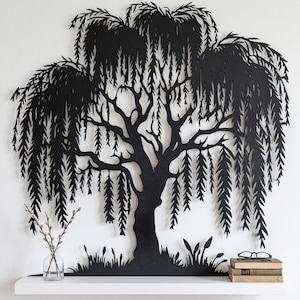 May include: Black metal willow tree wall art. The tree features a detailed silhouette of a weeping willow with cascading branches and leaves. The artwork is mounted on a white wall, with a shelf below holding a vase, books, and glasses.