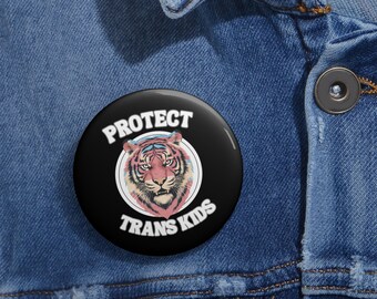 May include: A black button with a white border and the text "Protect Trans Kids" in white. A colorful tiger illustration is inside a circle in the center of the button.