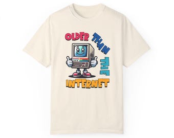 May include: A beige t-shirt featuring a cartoon computer wearing red shoes and the text "Older than the internet" in colourful letters.