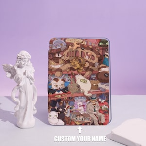 Könnte beinhalten: Eine personalisierte Handyhülle mit einer farbenfrohen Illustration verschiedener Katzenfiguren. Auf der Hülle stehen der Name "Monica" und der Text "CUSTOM YOUR NAME". Der Hintergrund ist helllila.