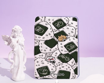 May include: A rectangular phone case with a repeating pattern of cartoon onigiri rice balls with nori seaweed. The design includes cute animal characters and Japanese text. The name "Monica" is printed on the case, along with the text "CUSTOM YOUR NAME".