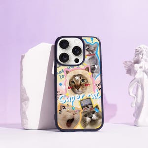 May include: A navy blue phone case with a collage of cartoon cat illustrations. The case has a yellow background with the words "Super cat" and other text. The case has a dark blue border and a camera cutout.