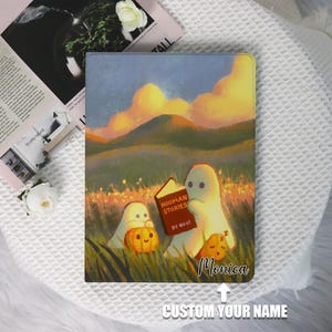 Könnte beinhalten: Eine personalisierte Tablet-Hülle mit einer skurrilen Illustration von zwei Geistern, die "HOOMAN STORIES BY BOO!" in einem Feld mit Kürbissen lesen. Die Hülle hat einen individuellen Namen und einen Landschaftshintergrund mit Sonnenuntergang.