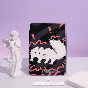 Peut inclure: Une coque rectangulaire avec un motif de chat blanc sur fond noir avec des accents roses. La coque porte les inscriptions "Monica" et "CUSTOM YOUR NAME". La coque est présentée sur une surface violette.