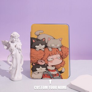 Op de afbeelding: Een gele tablethoes met een cartoonillustratie van een meisje met rood haar en drie katten. De naam van het meisje, "Monica", staat op de hoes. De tekst "CUSTOM YOUR NAME" is ook zichtbaar.