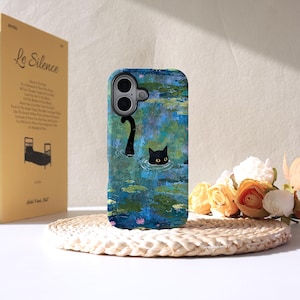 May include: A phone case with a black cat design in a pond, with a second cat tail visible. The case has a blue and green water lily painting style background. A book titled "Le Silence" is visible in the background.