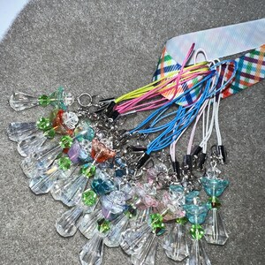 May include: A collection of crystal angel charms with colorful beads and strings. The charms are attached to colorful cords with silver clasps.