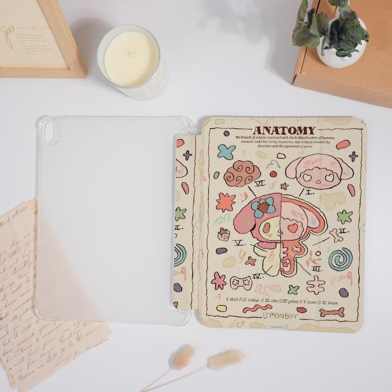 K&ouml;nnte beinhalten: Transparente Tablet-H&uuml;lle mit beigefarbenem Cover mit einem Cartoon-Anatomie-Design. Das Design umfasst eine rosa und gelbe Figur, anatomische Diagramme und das Wort "ANATOMY". Die H&uuml;lle ist offen und zeigt den Bildschirm des Tablets.