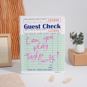 May include: A white and green guest check with the text "Guest Check" and "Can you play Taylor Swift?" in pink script. The check has a grid pattern and includes fields for date, amount, guests, and server.