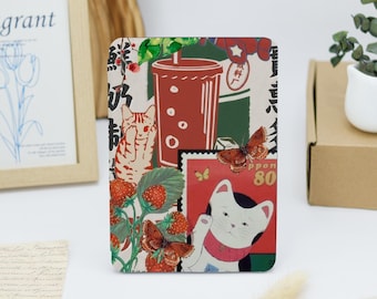 May include: A colorful phone case with a collage of images including a cat, a butterfly, a cup of tea, and a Japanese stamp. The case has a red, white, and green color scheme.