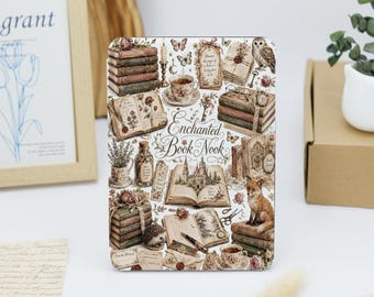 May include: A rectangular decorative plaque featuring the text Enchanted Book Nook surrounded by illustrations of stacked vintage books, an open book with a castle, a fox, an owl, a hedgehog, teacups, flowers, and a fountain pen.