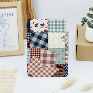 May include: A tablet case with a patchwork design, showcasing a mix of patterns such as gingham, polka dots, and floral motifs. The case is in shades of blue, red, and brown, with visible stitching between the fabric squares. The design evokes the look of a traditional quilt.