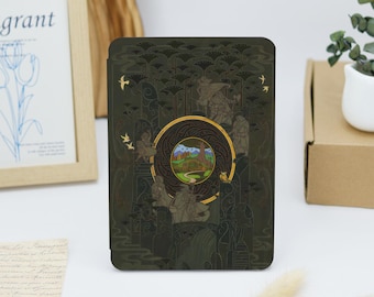 May include: A dark green Kindle cover with a gold and green illustration of a tree and a path leading to a mountain range. The illustration is surrounded by a gold circle with a black and gold pattern.