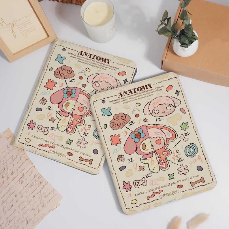K&ouml;nnte beinhalten: Zwei beige Tablet-H&uuml;llen mit einem Cartoon-Anatomie-Design. Das Design zeigt eine rosa und wei&szlig;e Figur mit anatomischen Illustrationen, Wolken und Sternen. Die Texte "ANATOMY" und "LEMONBOY" sind sichtbar.