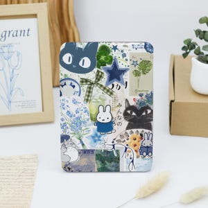 Könnte beinhalten: Eine Collage aus blauen und weißen Aufklebern auf weißem Hintergrund. Die Aufkleber zeigen eine Katze, ein Kaninchen, einen Stern, Blumen und japanischen Text.