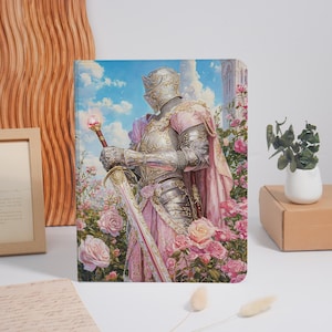 Könnte beinhalten: Ein rechteckiger Notizbuchumschlag mit einer Illustration eines Ritters in polierter silberner Plattenrüstung und einem rosa Umhang, der in einem Garten mit rosa Rosen steht. Der Ritter hält ein langes Schwert mit einer leuchtenden Kugel am Knauf.