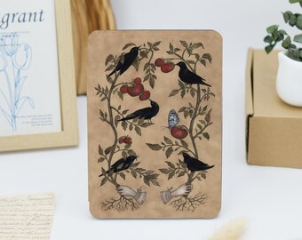 May include: A rectangular tablet case with a tan background featuring an illustration of two hands emerging from roots, holding tomato vines with red tomatoes, black birds perched on the branches, and a single blue and white butterfly.