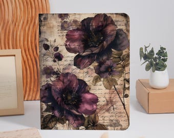 May include: A rectangular notebook cover featuring a vintage-inspired design with large, dark purple flowers and green leaves layered over a background of faded, handwritten cursive script text in black ink on a beige, parchment-like surface.