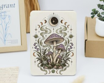 May include: A rectangular e-reader case featuring a detailed illustration of purple mushrooms, green foliage, and celestial elements including a crescent moon, stars, and planetary rings on a cream-colored background.