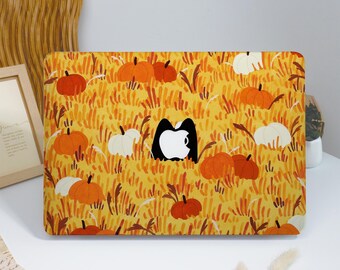 May include: A laptop skin featuring a vibrant autumn pattern of orange and white pumpkins nestled in tall yellow grass. The design includes a central cutout revealing the white Apple logo, surrounded by a repeating harvest-themed illustration.