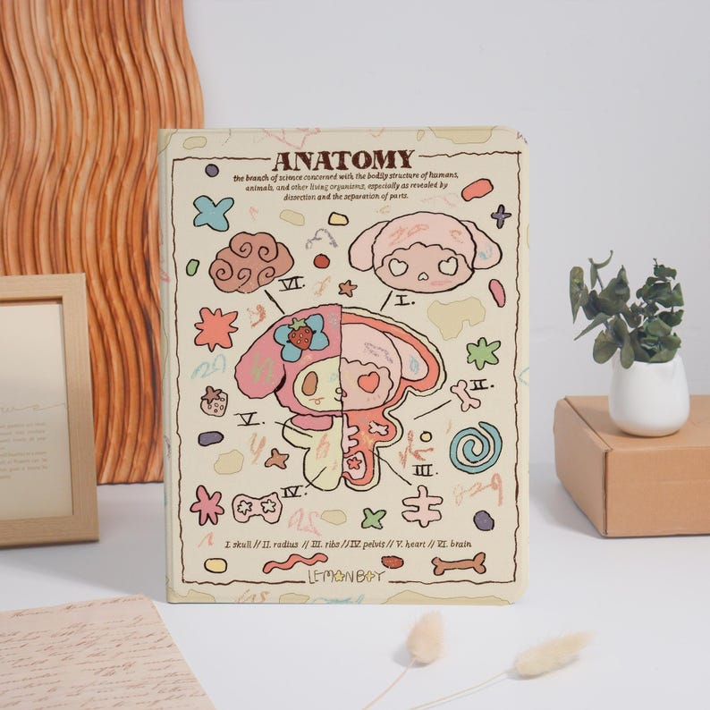 K&ouml;nnte beinhalten: Ein beigefarbenes Notizbuch mit dem Wort "ANATOMY" oben, das eine Cartoon-Illustration eines Charakters mit anatomischen Details zeigt. Das Notizbuch hat einen cremefarbenen Hintergrund mit verschiedenen Kritzeleien und dem Text "LEMONBAY" unten.
