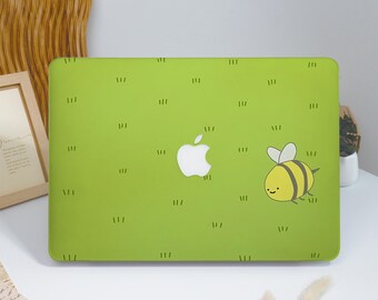 May include: A lime green laptop hard shell case featuring a repeating pattern of small black grass tufts and a single cartoon bee with yellow and black stripes, white wings, and a smiling face, centered around the white Apple logo.