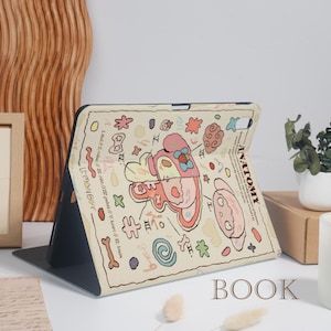 K&ouml;nnte beinhalten: Eine beige Tablet-H&uuml;lle mit einer farbenfrohen anatomischen Illustration. Die H&uuml;lle hat ein skurriles Design mit verschiedenen Formen, Text und dem Wort "ANATOMY". Das Wort "BOOK" ist unten aufgedruckt.