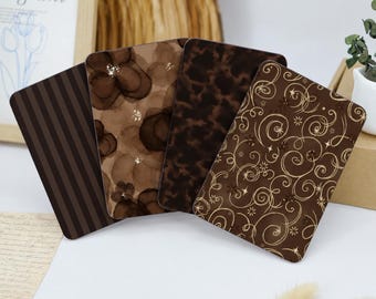 May include: Four rectangular cards arranged in a fan shape. The first features dark brown vertical stripes, the second has brown watercolor-style floral shapes with gold accents, the third displays a dark brown tortoiseshell pattern, and the fourth has a brown background with gold swirling lines and small star motifs.
