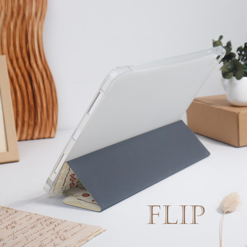 K&ouml;nnte beinhalten: Eine transparente Tablet-H&uuml;lle mit grauem Klappdeckel. Der Deckel ist hochgeklappt und st&uuml;tzt das Tablet in einem Winkel. Der untere Rand des Covers hat ein Muster. Das Wort "FLIP" ist braun gedruckt.