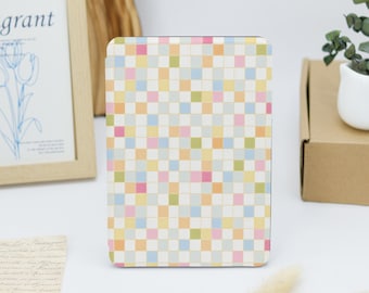 May include: A rectangular e-reader case featuring a repeating grid pattern of small squares in pastel shades of yellow, pink, blue, green, and white. The case has a smooth, flat surface and rounded corners, displaying a consistent geometric design.