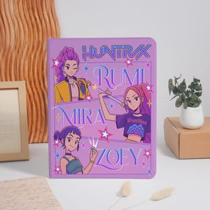 May include: A purple tablet case featuring anime-style illustrations of four women with the names Huntrix, Rumi, Mira, and Zoey. The case has a glossy finish and a decorative design with stars and text.