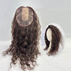 Puede incluir: Un postizo de cabello rizado marrón con una base de encaje y clips para sujetarlo. El postizo está diseñado para añadir volumen y longitud al cabello existente. Se muestra una pantalla más pequeña del postizo en una cabeza de maniquí.