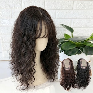 May include: A dark brown wavy hair topper with a center part and wispy bangs on a mannequin head. The hair features a natural texture and layered cut. Two smaller circular insets show the underside of the hair piece with clips and mesh base.