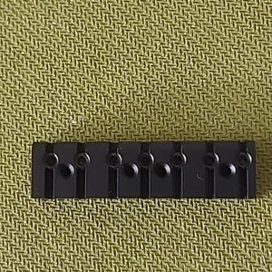 Puede incluir: Puente de guitarra de metal negro con seis selletas individuales. El puente está diseñado para seis cuerdas y tiene un acabado negro.