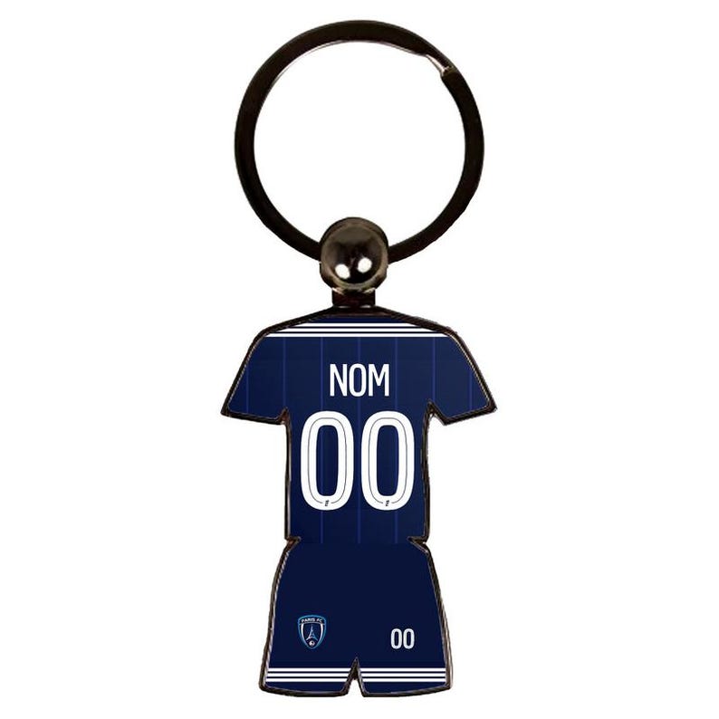 May include: A navy blue soccer jersey keychain with the word "NOM" and the number "00" in white. The keychain has a silver ring and a small ball at the top.