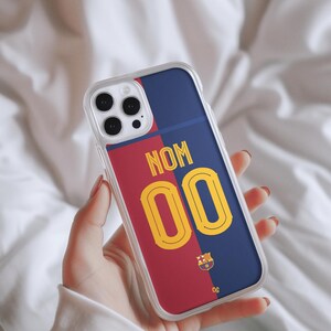 May include: A clear phone case with a red and blue design. The case features a soccer jersey design with the number "00" and the text "NOM". The case also features the FC Barcelona logo.
