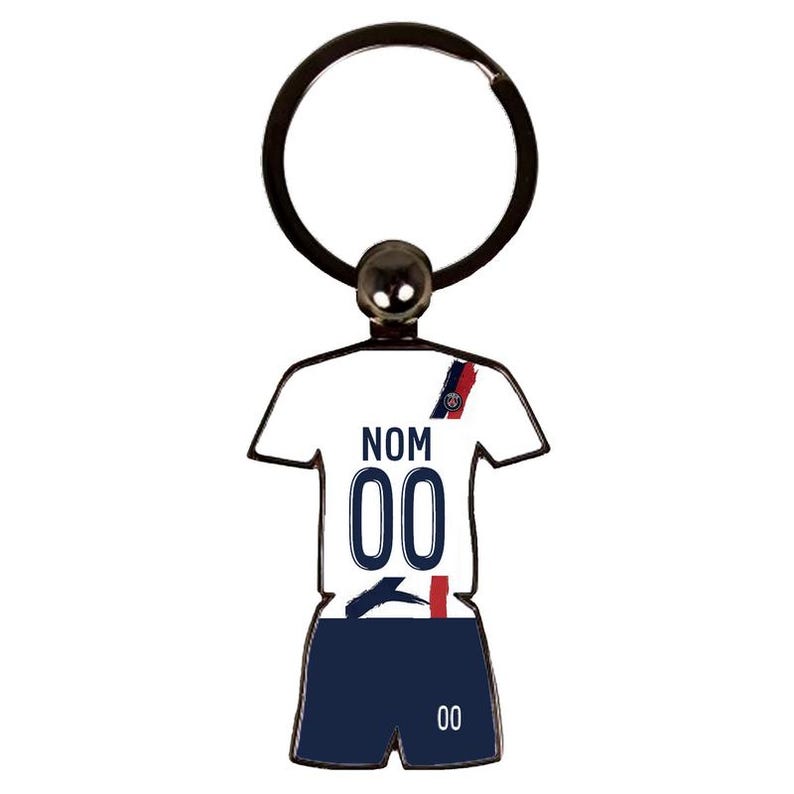 May include: A metal keychain in the shape of a soccer jersey and shorts. The jersey is white with the word "NOM" and the number "00" printed on it. The shorts are navy blue with the number "00" printed on them. The keychain has a black ring.